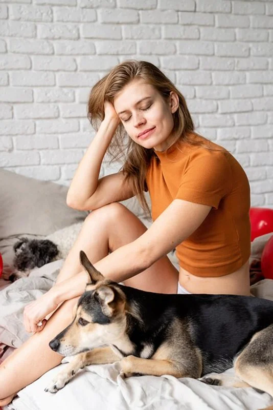Kobieta siedzi na łóżku ze swoim psem w domu