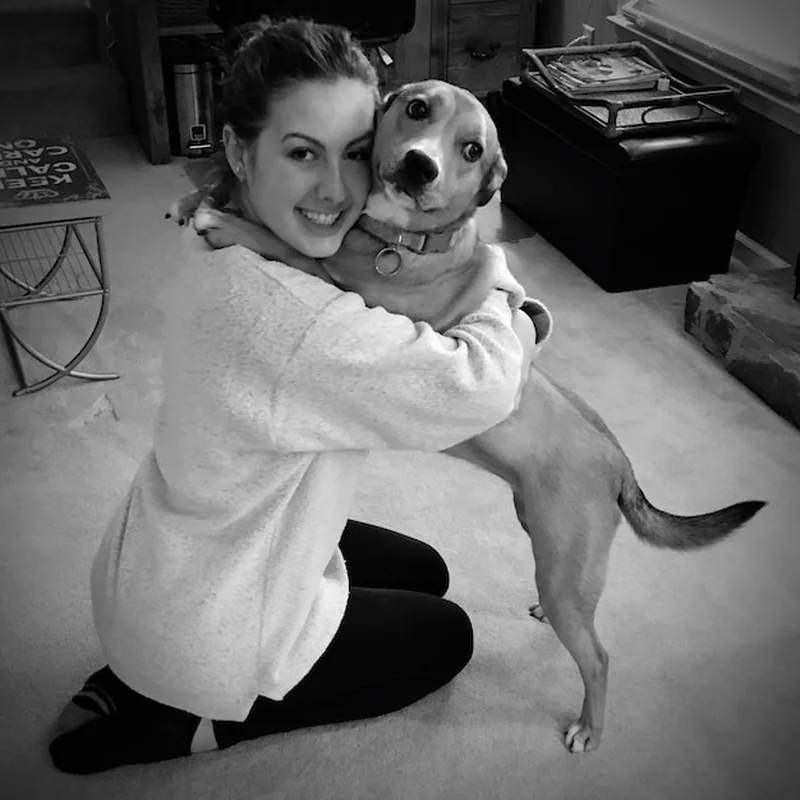 Uśmiechnięta kobieta uściskująca psa w domu