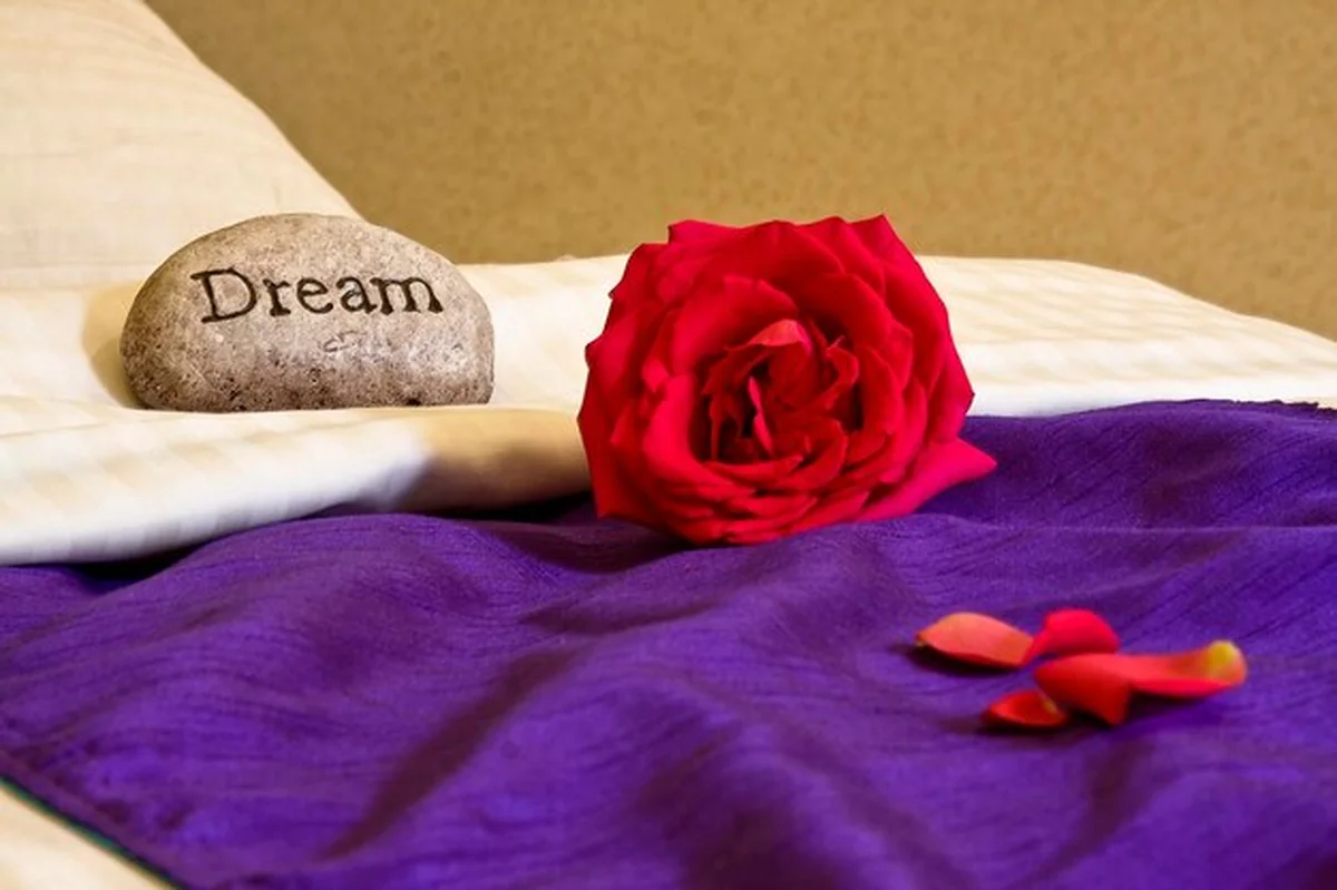 Dekoracja w spa z kamieniem, czerwoną różą i płatkami róż